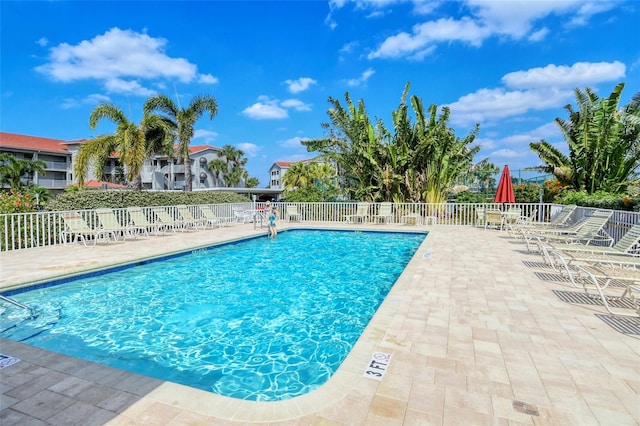 community pool with a patio area and fence
