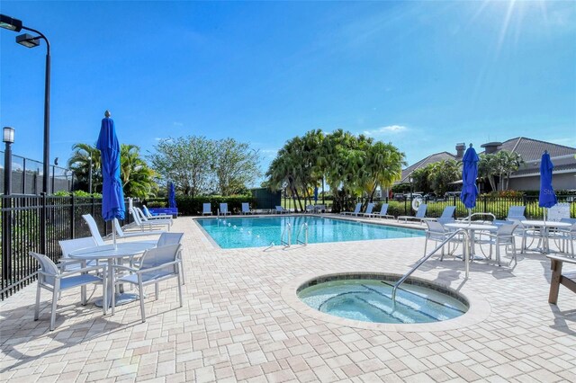 community pool featuring fence, a hot tub, and a patio