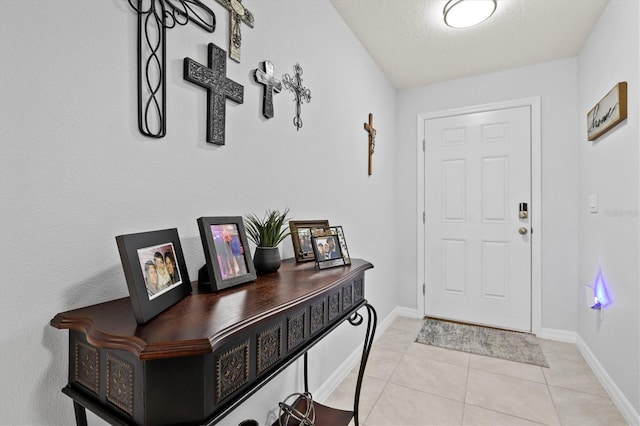 doorway with light tile patterned floors and baseboards