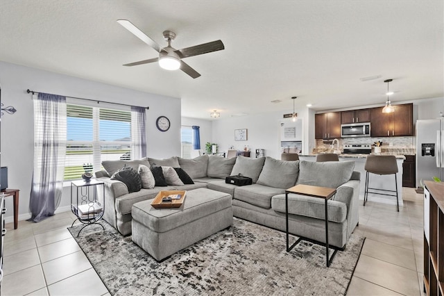 living room with ceiling fan, light tile patterned flooring, and baseboards