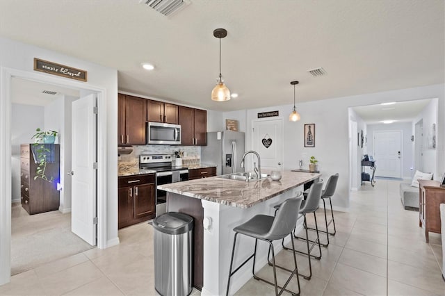 kitchen featuring stainless steel appliances, a sink, dark brown cabinetry, and light tile patterned floors