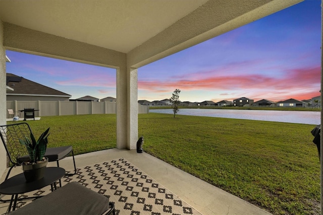 patio terrace at dusk featuring a water view and a residential view