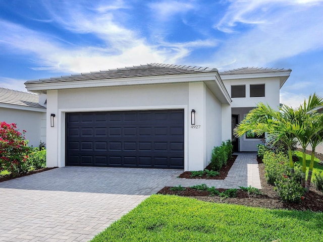 view of front of home featuring stucco siding, decorative driveway, and an attached garage