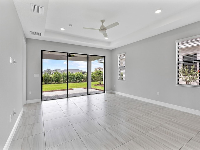 empty room with a tray ceiling, ceiling fan, baseboards, light tile patterned flooring, and recessed lighting