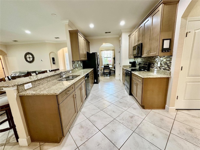 1568 Cordgrass Way, Lakeland, FL 33813 - kitchen with black appliances, arched walkways, a breakfast bar area, decorative backsplash, and crown molding