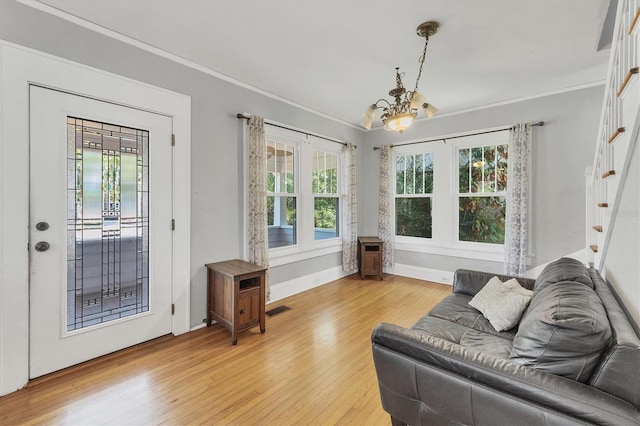 living area featuring a chandelier, light wood-style floors, stairs, healthy amount of natural light, and ornamental molding