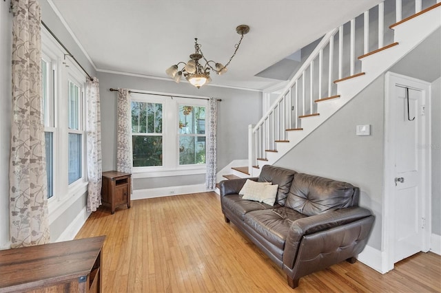 living area featuring a chandelier, stairway, light wood-type flooring, baseboards, and ornamental molding