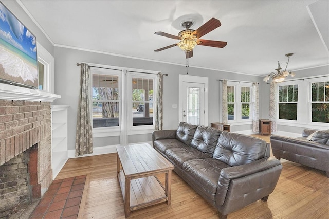 living room featuring wood finished floors, ceiling fan, crown molding, and a brick fireplace