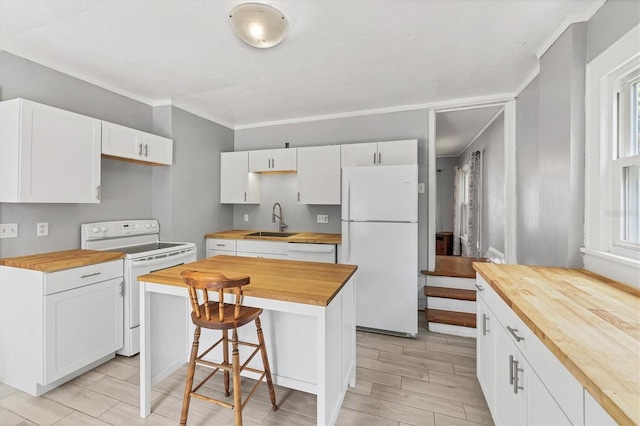 kitchen with wooden counters, white appliances, a sink, white cabinets, and a breakfast bar