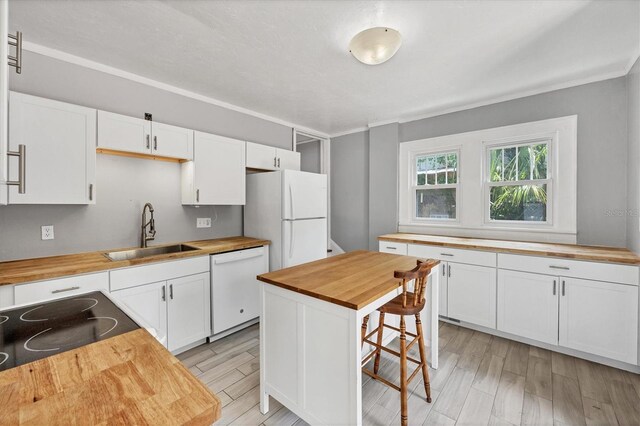 kitchen featuring wood counters, a sink, white appliances, and white cabinetry