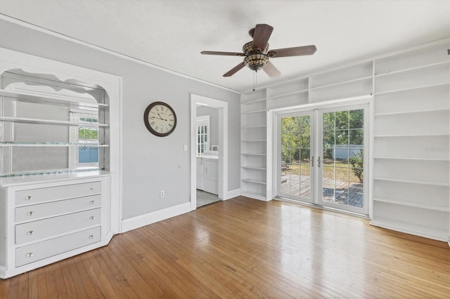 spare room with built in shelves, hardwood / wood-style floors, baseboards, and ceiling fan