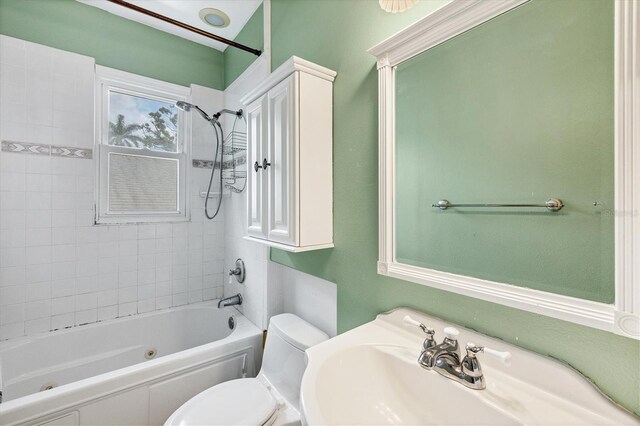 full bath featuring toilet, a combined bath / shower with jetted tub, and a sink