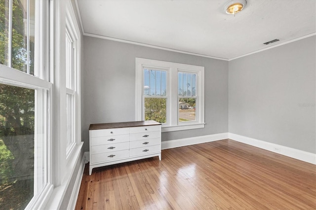 unfurnished room featuring ornamental molding, hardwood / wood-style floors, and baseboards
