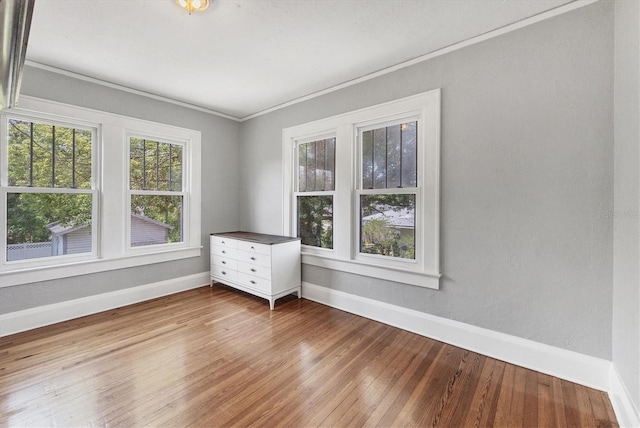 spare room featuring baseboards, hardwood / wood-style flooring, and ornamental molding