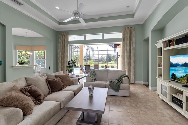 1542 Ormond Ter, Parrish, FL 34219 - living room featuring a ceiling fan, crown molding, a tray ceiling, light tile patterned floors, and baseboards