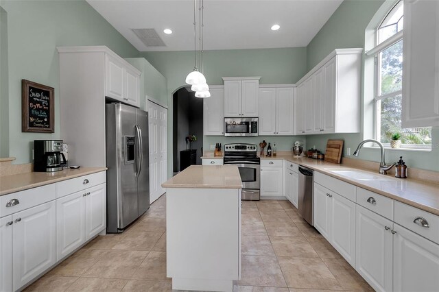 1542 Ormond Ter, Parrish, FL 34219 - kitchen with stainless steel appliances, a sink, a kitchen island, white cabinetry, and light countertops