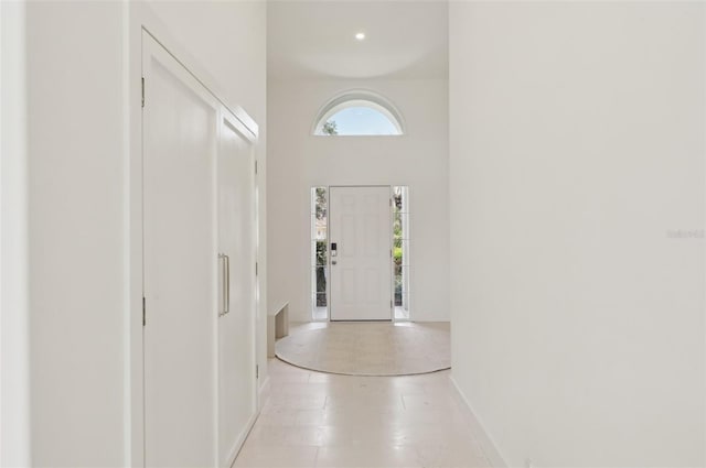 foyer with baseboards and a towering ceiling
