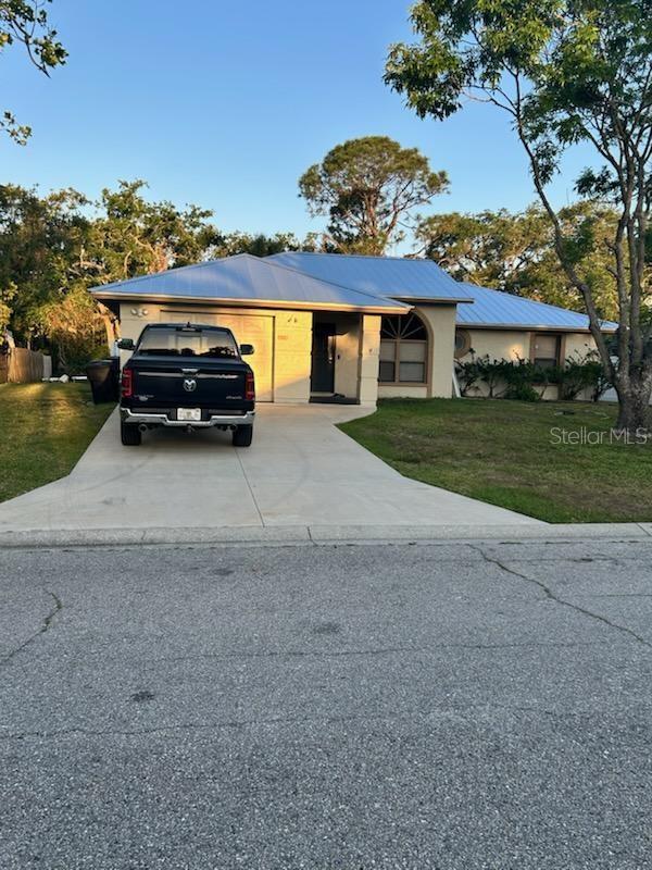 ranch-style house featuring concrete driveway, a front yard, and an attached garage