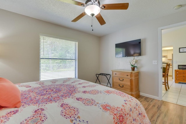 bedroom featuring wood finished floors, a textured ceiling, ceiling fan, and baseboards