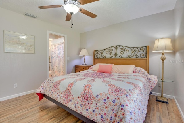 bedroom featuring wood finished floors, baseboards, ensuite bathroom, and ceiling fan