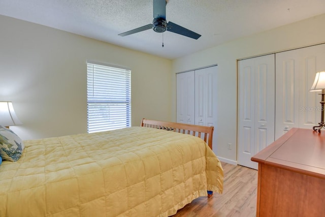 bedroom with light wood-style floors, multiple closets, ceiling fan, and a textured ceiling