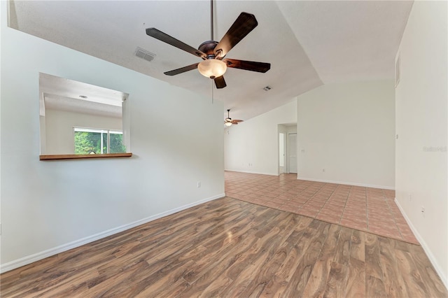 empty room featuring wood finished floors, ceiling fan, vaulted ceiling, and baseboards