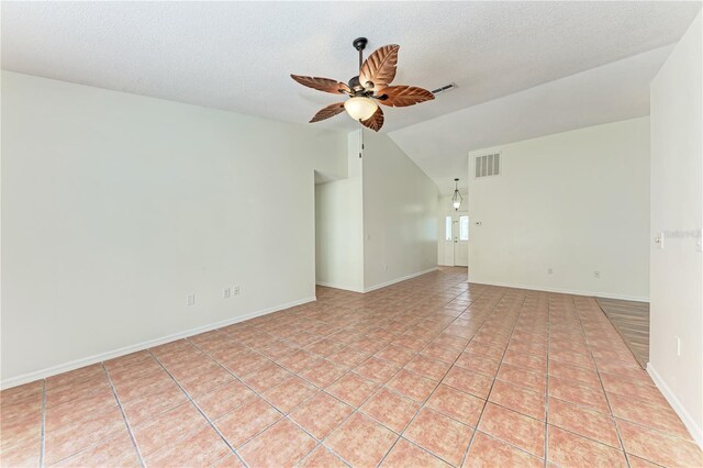 spare room with a ceiling fan, vaulted ceiling, baseboards, a textured ceiling, and light tile patterned floors