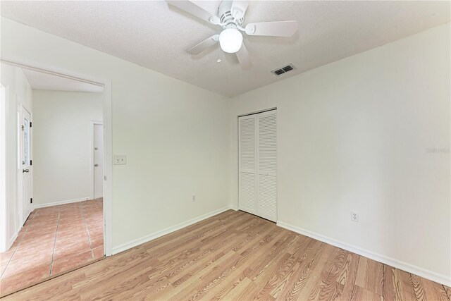 unfurnished bedroom featuring a closet, light wood-style floors, baseboards, and a ceiling fan