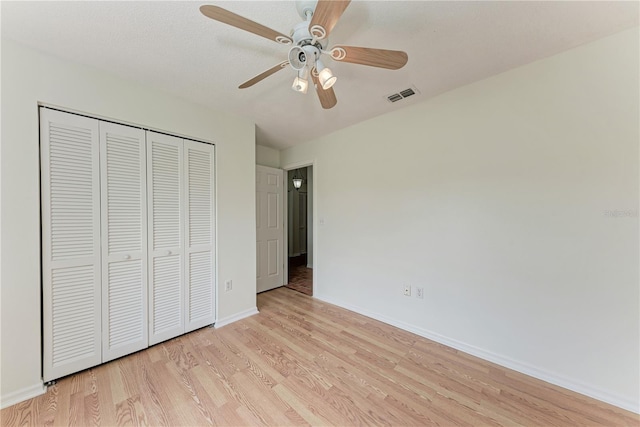 unfurnished bedroom with baseboards, light wood finished floors, a closet, and ceiling fan