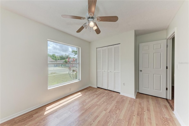 unfurnished bedroom featuring light wood-type flooring, a closet, baseboards, and ceiling fan