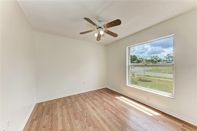 unfurnished room featuring light wood-style flooring, ceiling fan, baseboards, and a textured ceiling