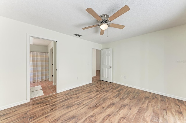 unfurnished bedroom with wood finished floors, baseboards, a textured ceiling, and ceiling fan