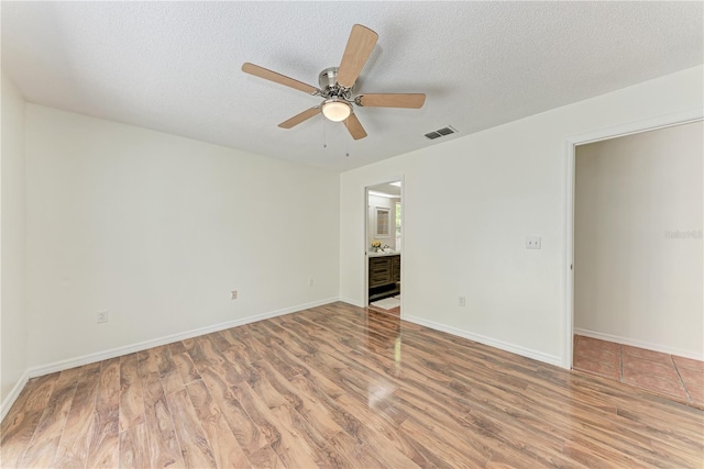 unfurnished room featuring light wood-type flooring, ceiling fan, a textured ceiling, and baseboards