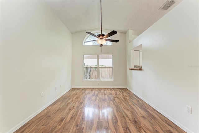 empty room featuring a ceiling fan, lofted ceiling, wood finished floors, and baseboards