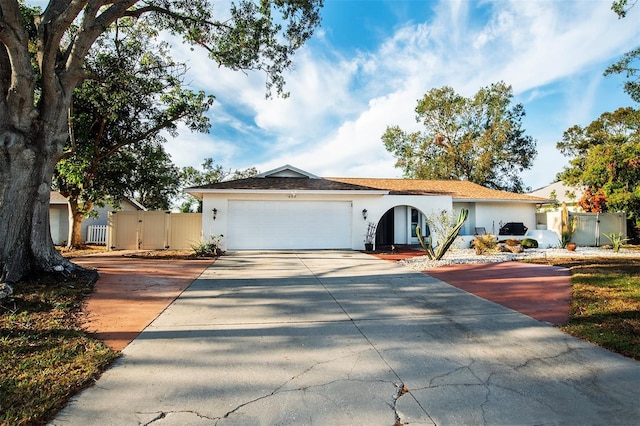 view of front of home with stucco siding, an attached garage, driveway, and fence