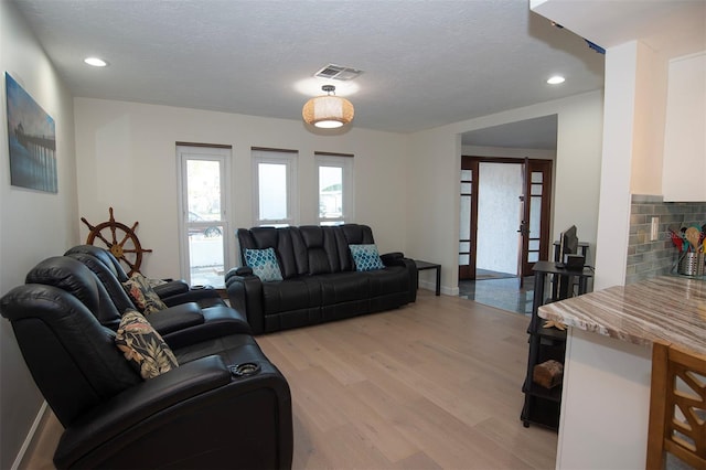 living room with light wood finished floors, a fireplace, recessed lighting, a textured ceiling, and baseboards