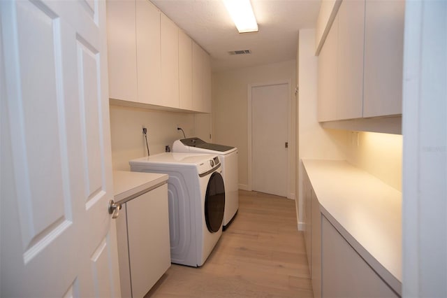 laundry area featuring cabinet space, washer and clothes dryer, and light wood-type flooring