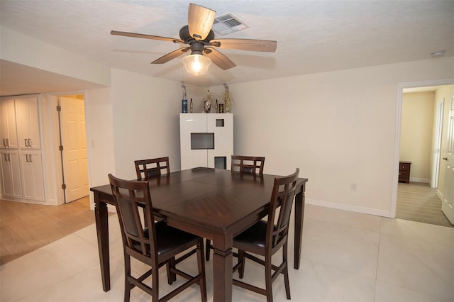 dining area with light tile patterned floors, a ceiling fan, and baseboards
