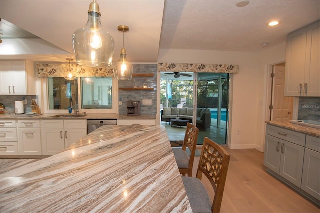 kitchen featuring a sink, stainless steel dishwasher, light wood-type flooring, decorative backsplash, and recessed lighting