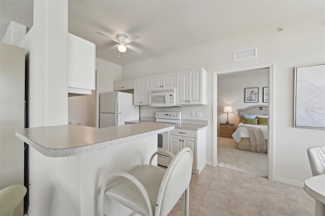 kitchen featuring white appliances, a ceiling fan, light countertops, a peninsula, and baseboards