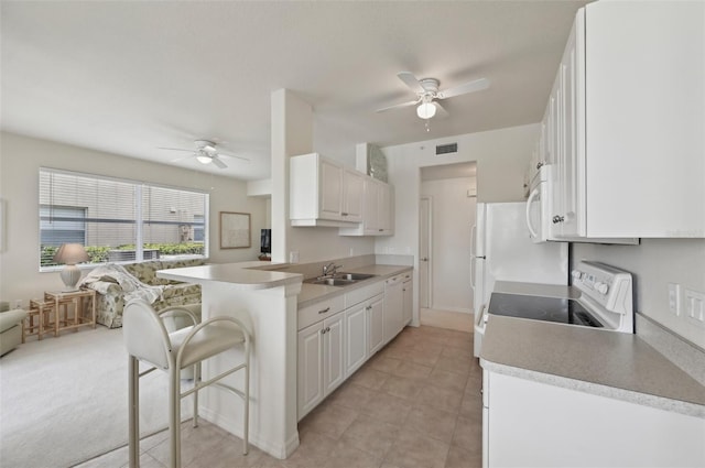 kitchen featuring white appliances, ceiling fan, a sink, a kitchen bar, and a peninsula
