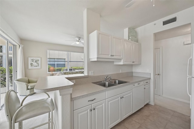 kitchen with white appliances, a ceiling fan, a sink, a breakfast bar area, and light countertops