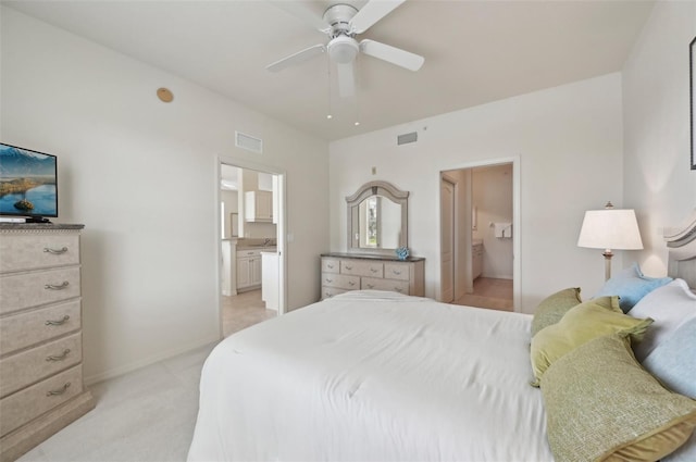 bedroom with ensuite bathroom, light colored carpet, baseboards, and a ceiling fan