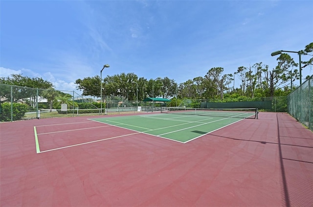 view of tennis court with community basketball court and fence