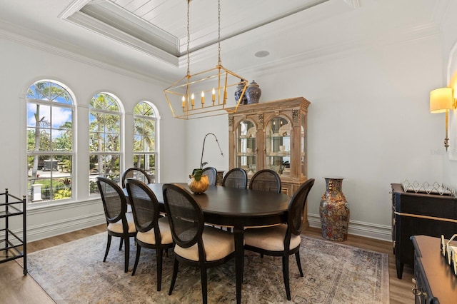 dining space featuring a tray ceiling, a chandelier, crown molding, wood finished floors, and baseboards