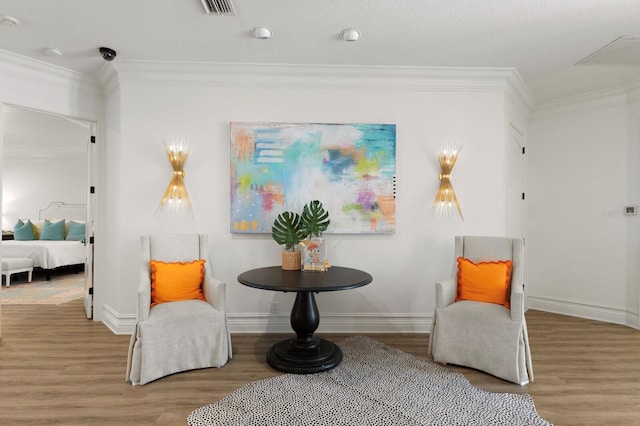 living area with wood finished floors, ornamental molding, and baseboards