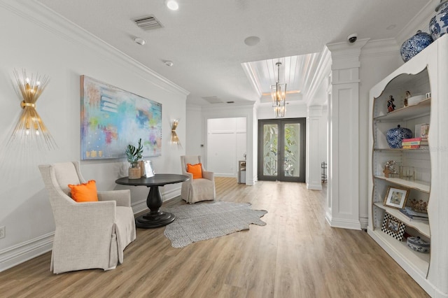 entrance foyer with crown molding, light wood-type flooring, baseboards, decorative columns, and french doors