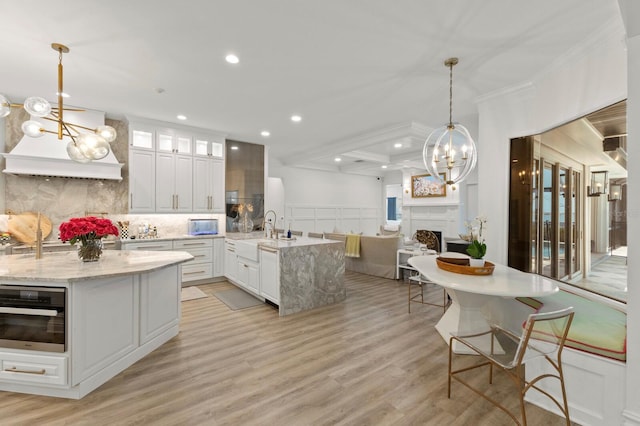 kitchen featuring wall oven, a chandelier, a fireplace, a sink, and recessed lighting