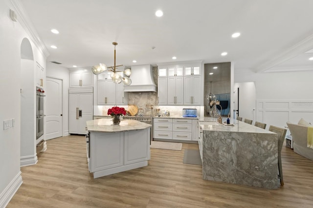 kitchen with premium range hood, paneled built in refrigerator, backsplash, a center island, and crown molding
