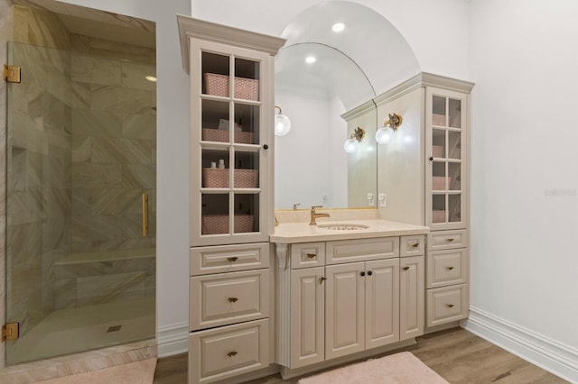full bath featuring a shower stall, wood finished floors, vanity, baseboards, and recessed lighting